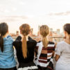 A line of women standing against a city sky line