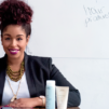 Woman with natural hair sitting with Aveda products