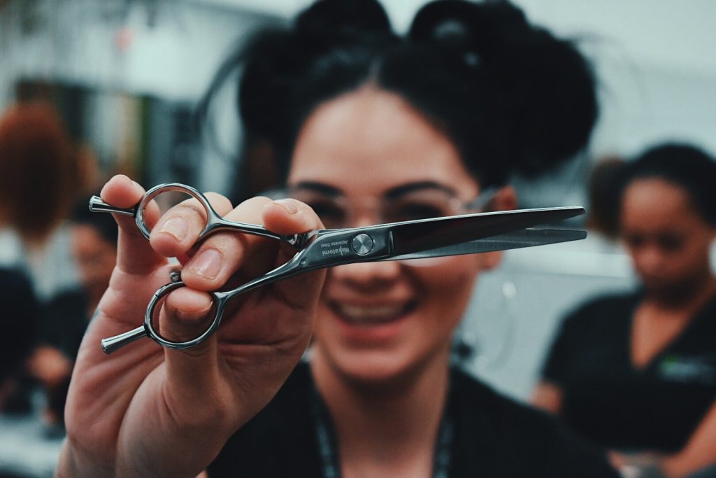 Cosmetologist holding pair of scissors