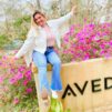 Woman sitting on sign for Aveda institute