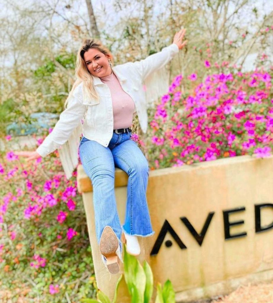 Woman sitting on sign for Aveda institute